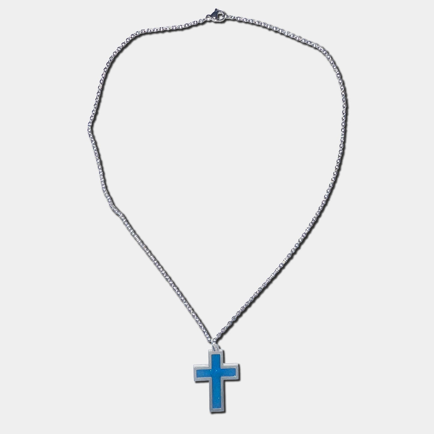 Stainless steel necklace with blue cross pendant on a white background