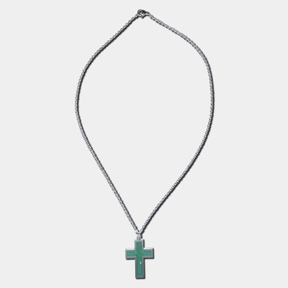 Stainless steel necklace with green cross pendant on a white background